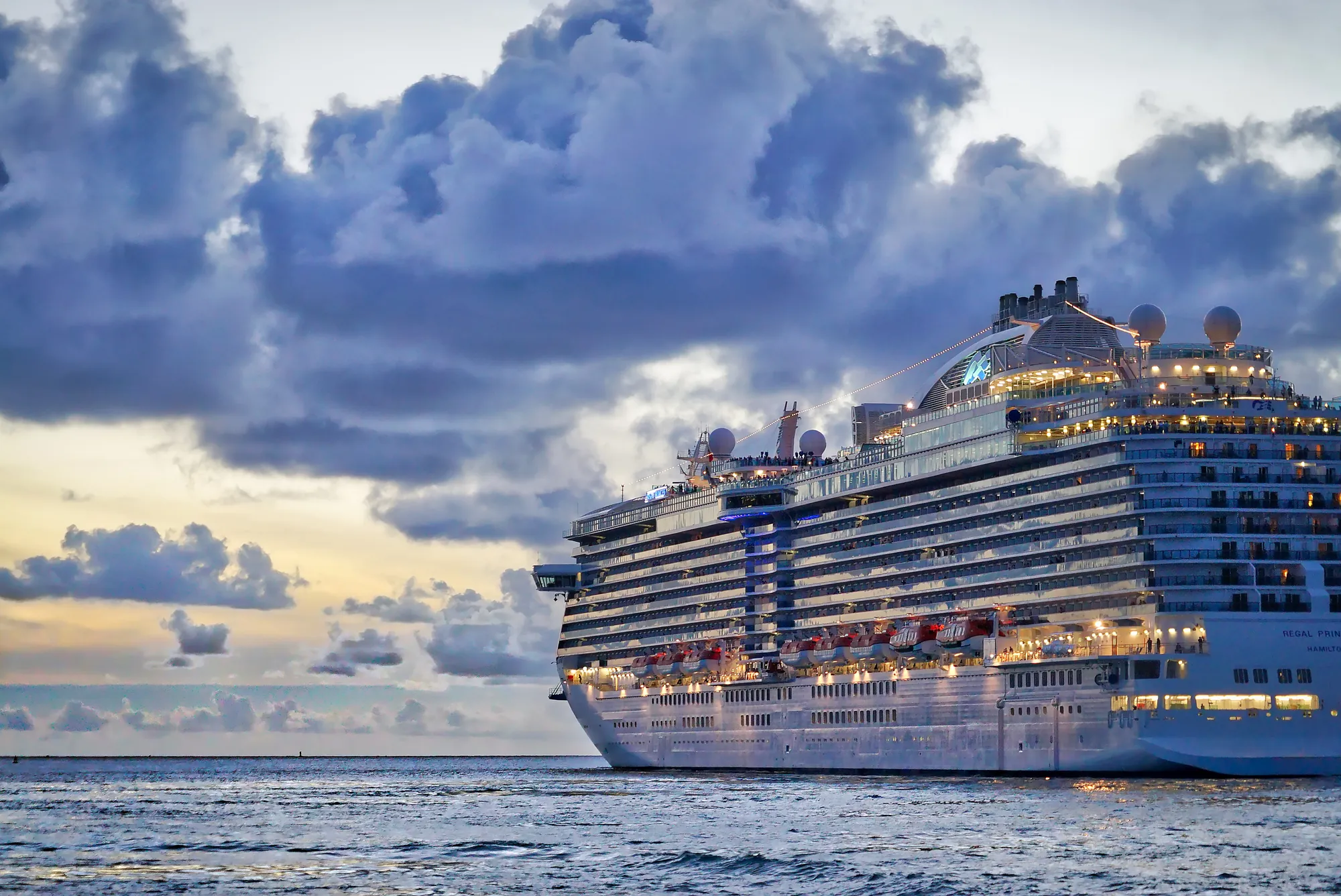 A large cruise ship at sea under dramatic clouds