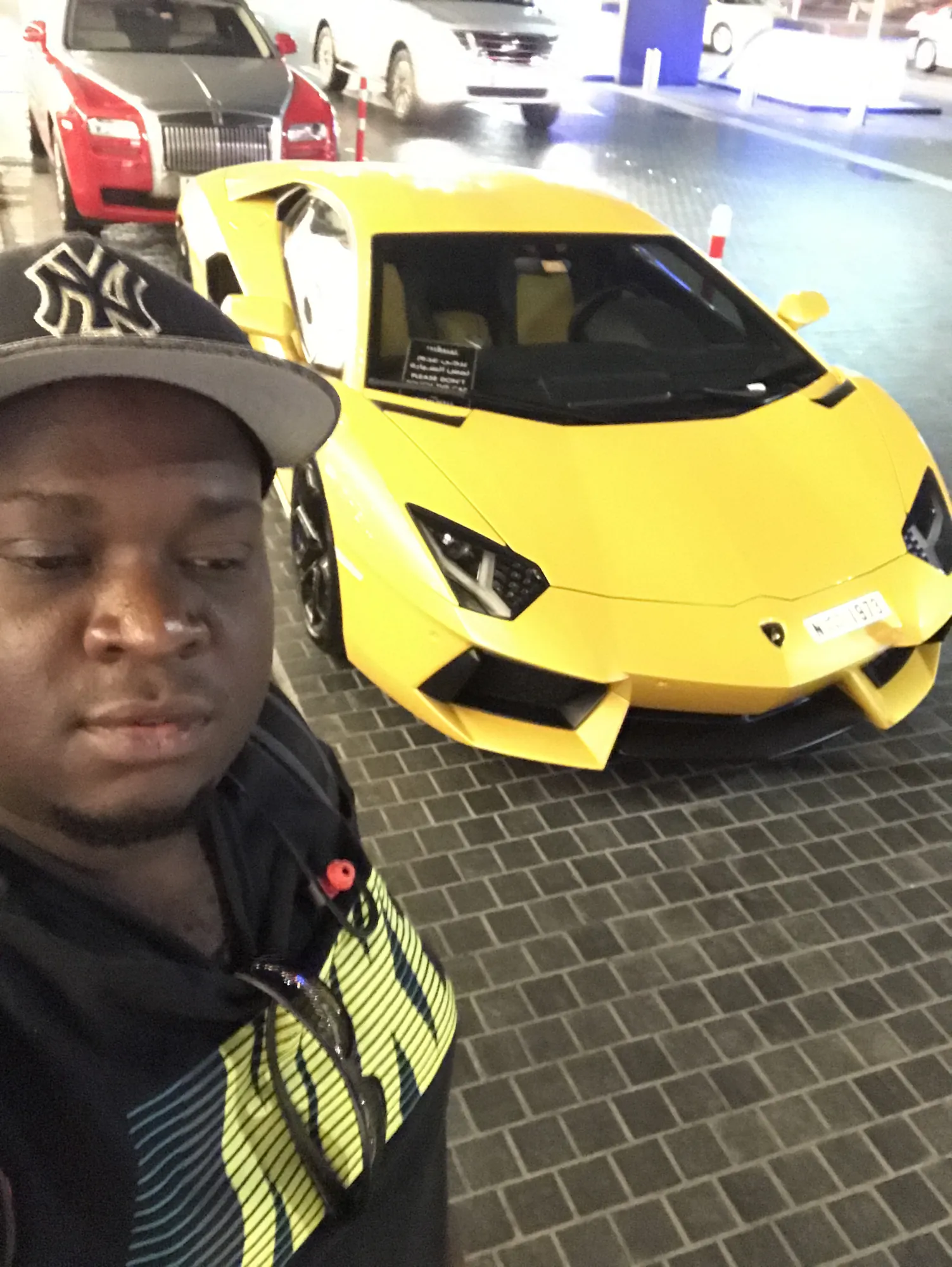 Asong taking a selfie with a yellow Lamborghini Aventador in Dubai