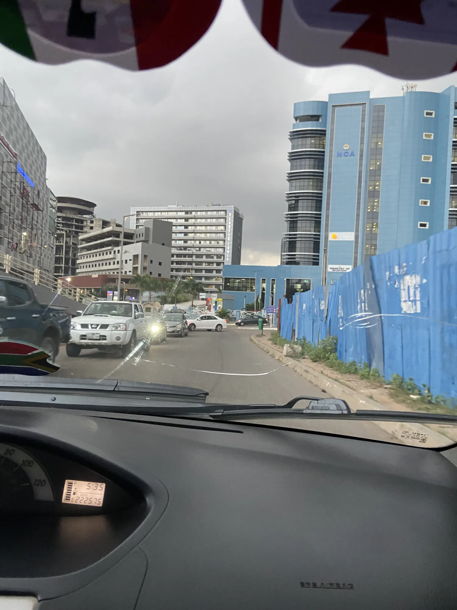 A busy Accra road lined with new office towers, seen from the car