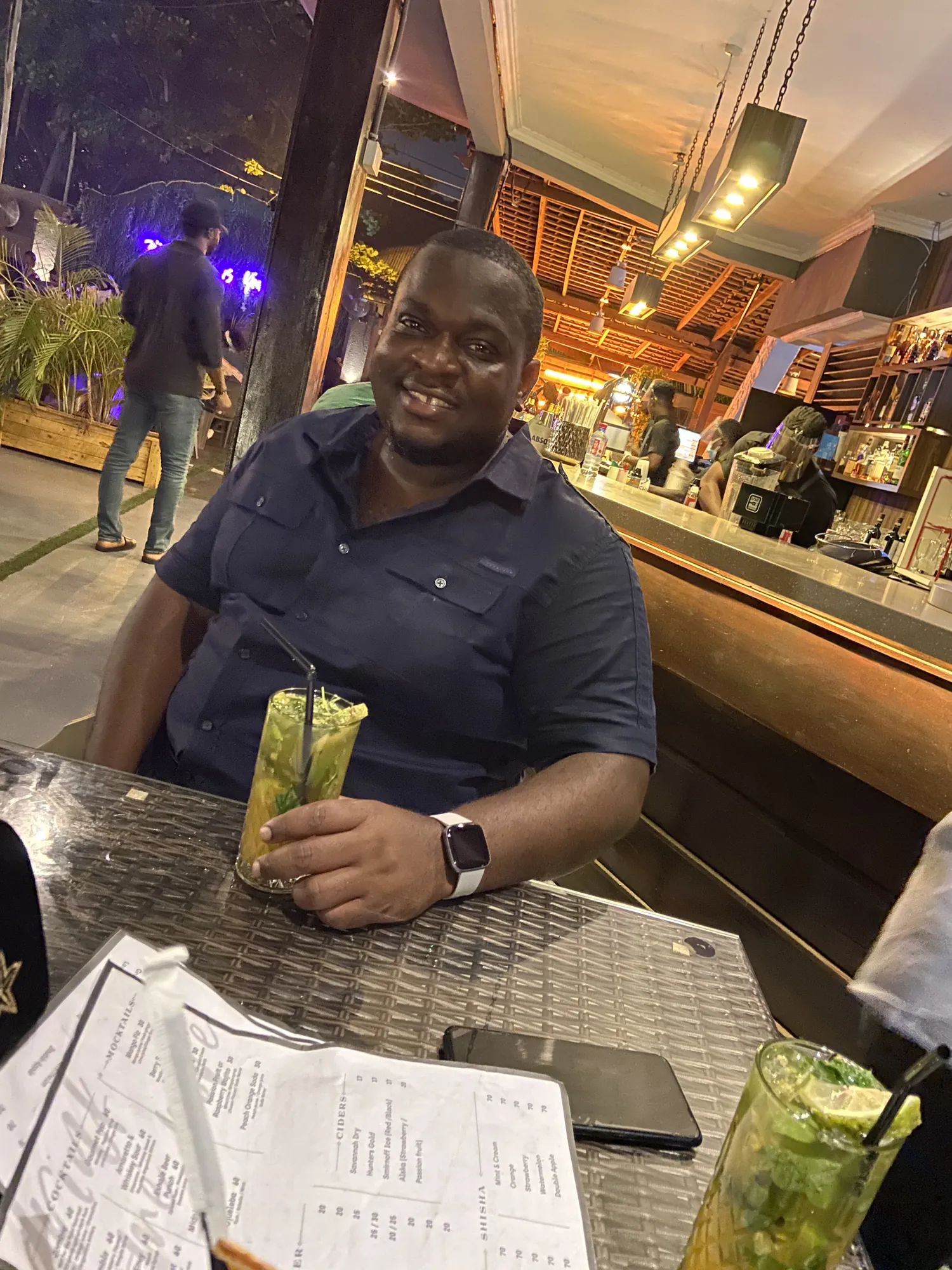 Asong smiling at a bar table with a mojito on a night out in Ghana