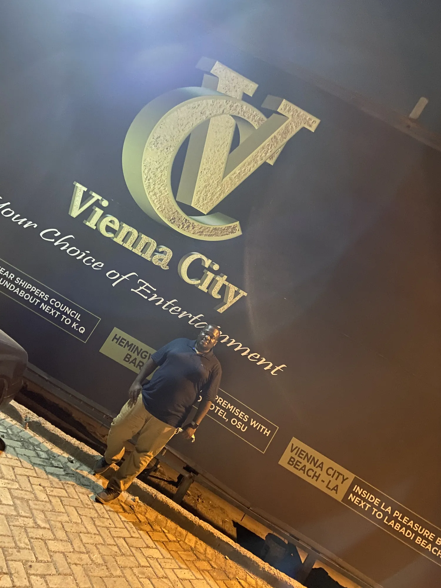 Asong beneath the gold Vienna City sign in Accra