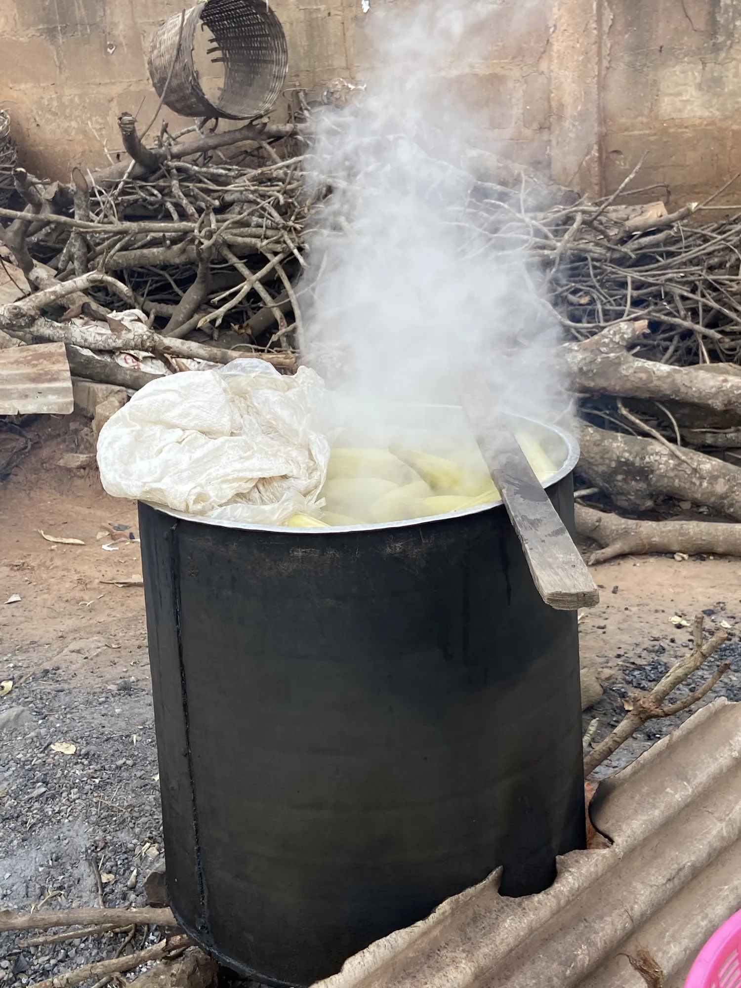 A steaming cooking pot over a wood fire in a Ghanaian village