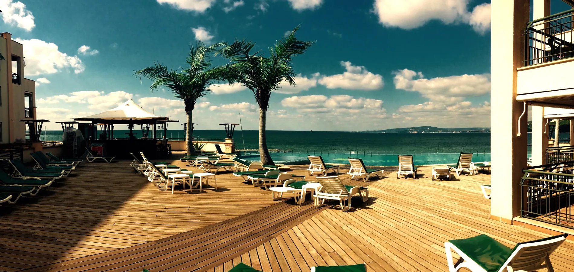 Resort pool deck with loungers and palms beside the sea