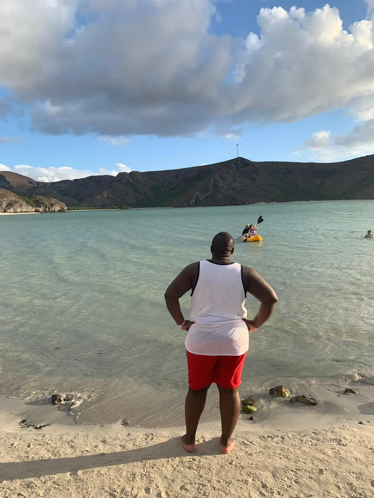 Asong on the sand watching kayakers cross a calm Baja bay