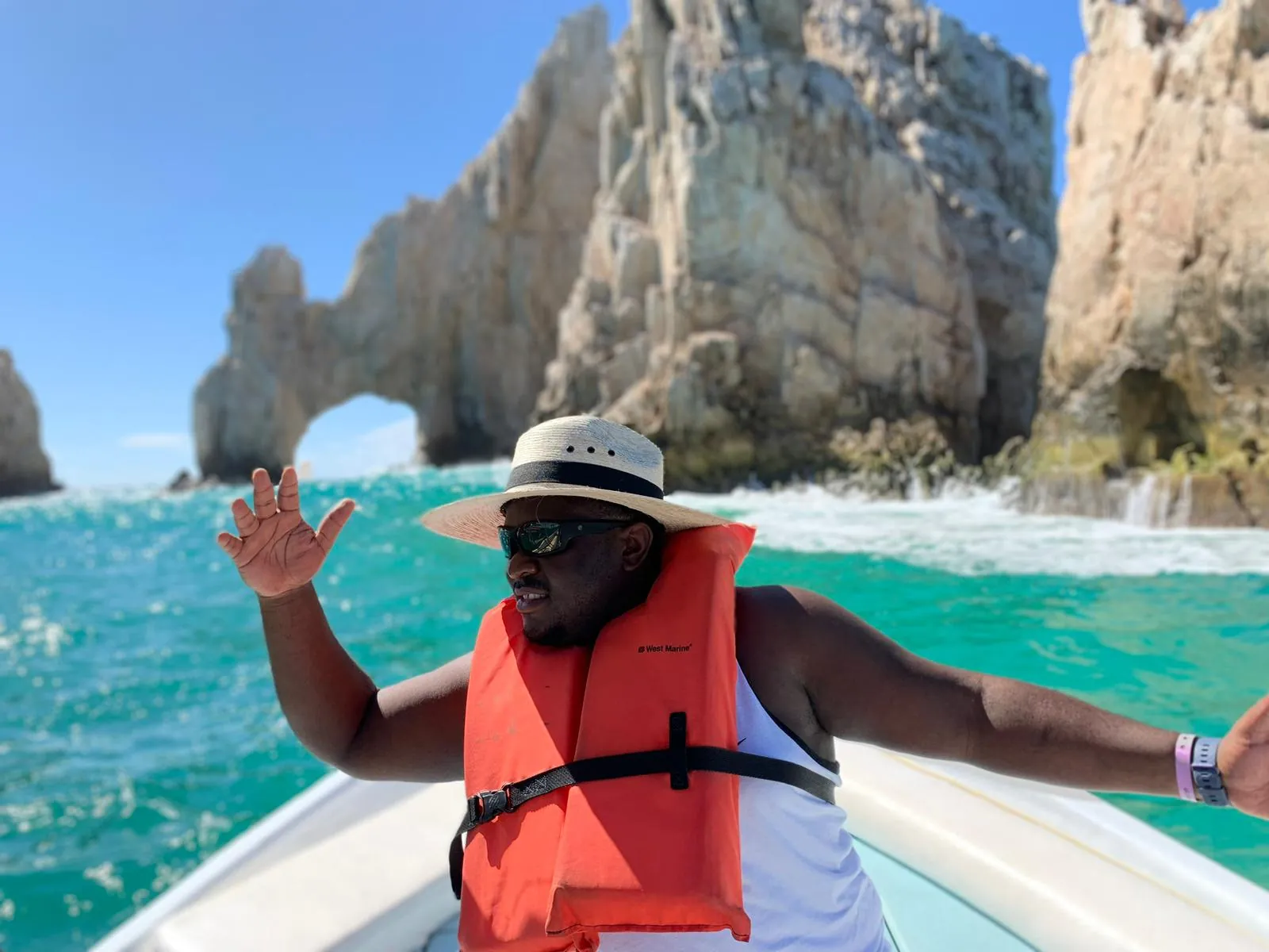 Asong waving from the boat beside the rock arch of Land's End, Cabo