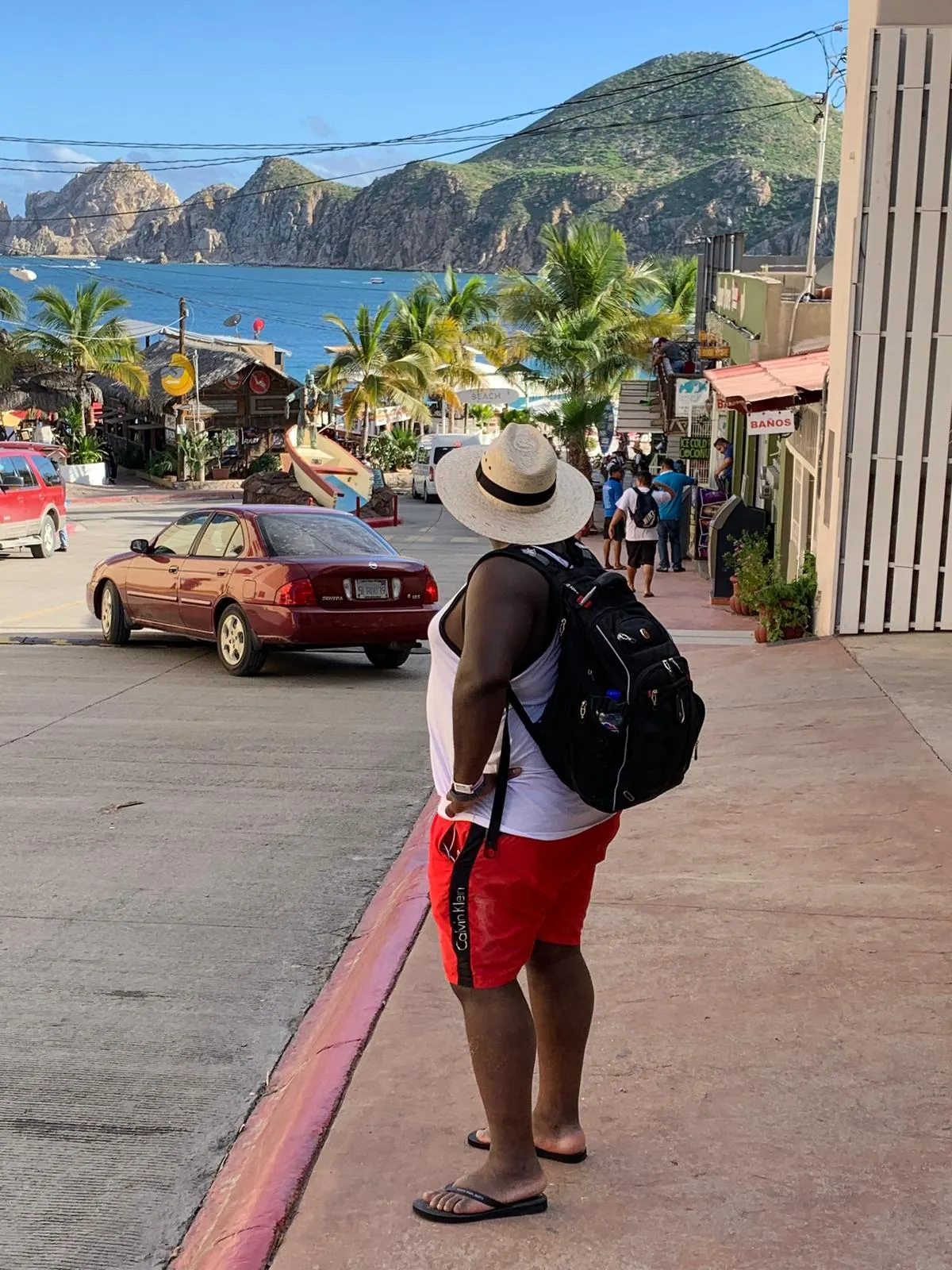 Asong with a backpack on a palm-lined Cabo San Lucas street
