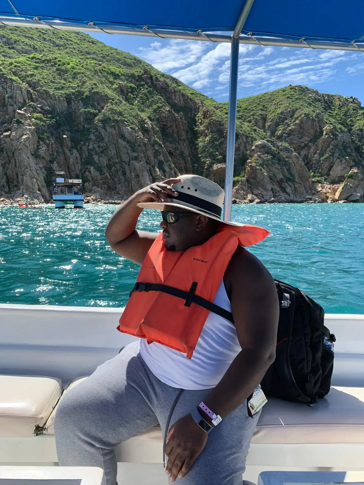 Asong in a sun hat and life jacket on a Cabo water taxi