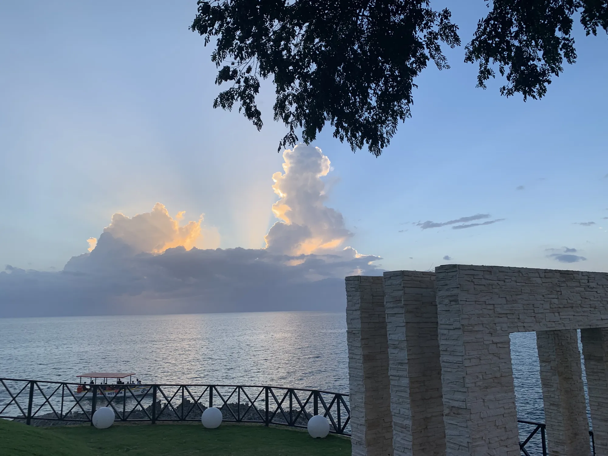 Towering clouds lit gold above the sea wall at a Negril sunset