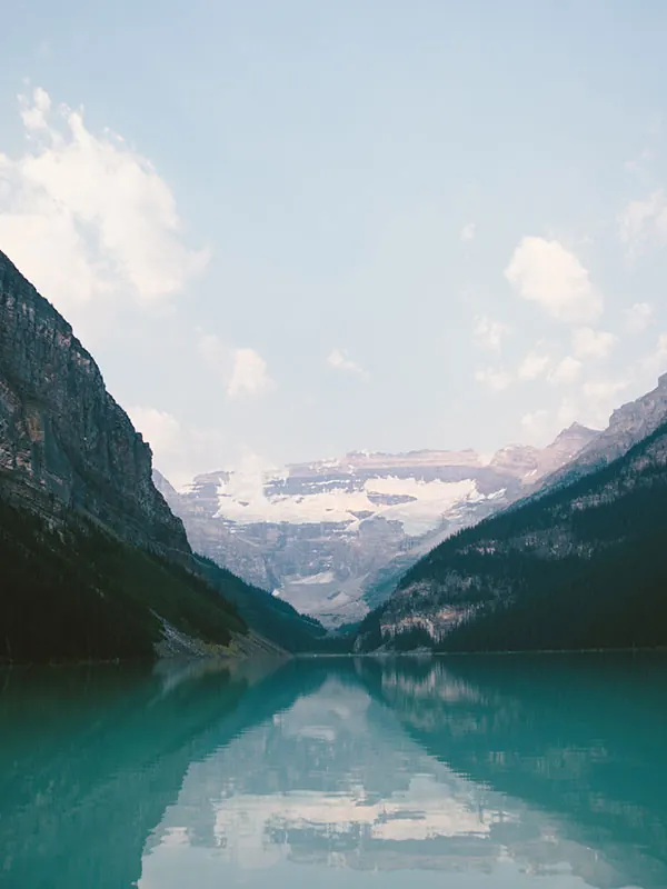 A glacial lake in a wooded valley between steep mountains