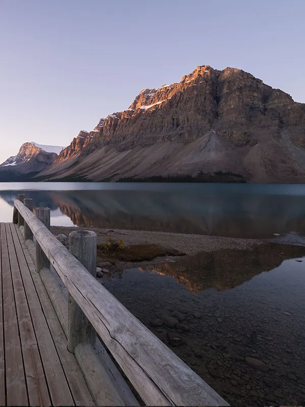 A wooden jetty running into a mountain lake at sunset